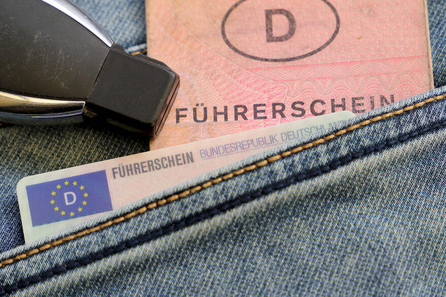 Ein alter und ein neuer deutscher Führerschein mit der Aufschrift 'Führerschein' in einer Hosentasche sowie ein Autoschlüssel.