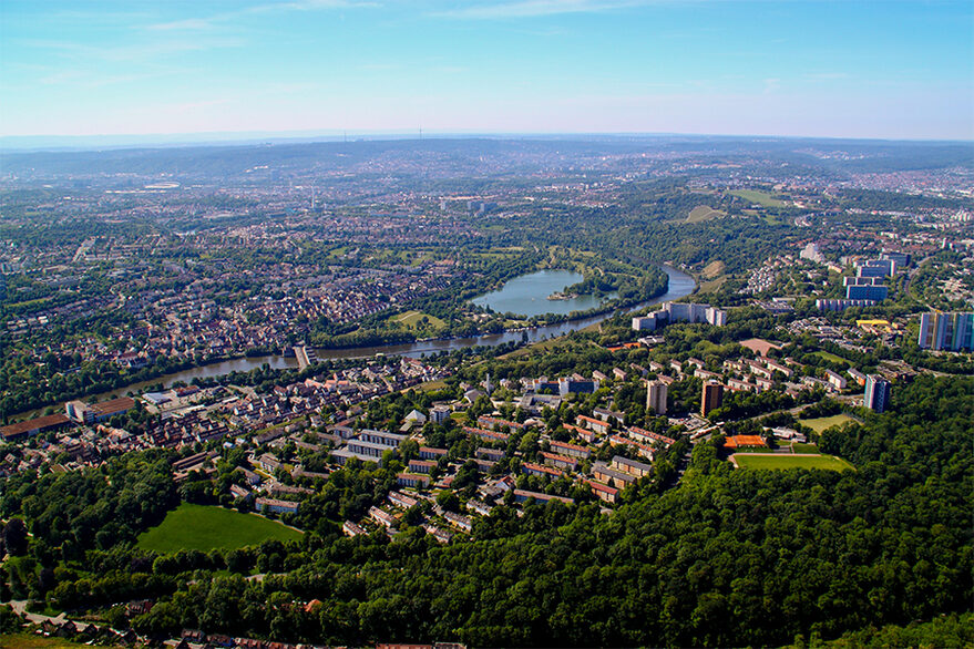 Luftbild von Stuttgart-Mühlhausen mit Häusern, Wald, einem Fluss und und einem See.