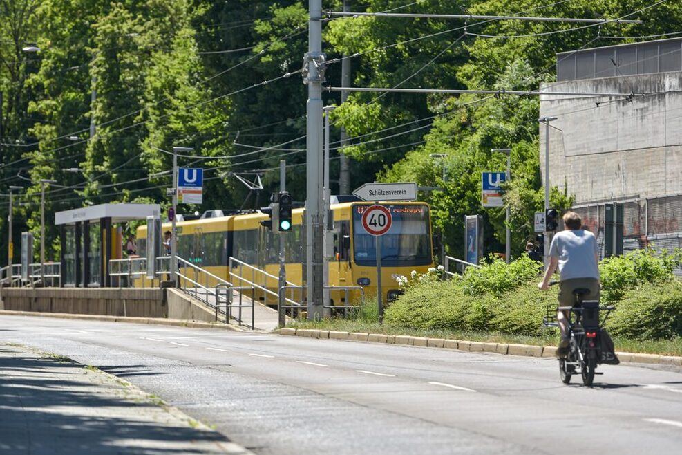 Ein Fahrrad fährt auf der Straße, im Hintergrund fährt eine U-Bahn