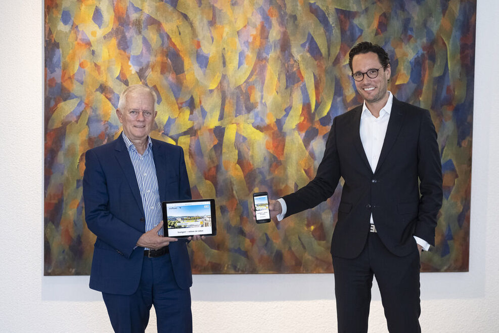 Oberbürgermeister Fritz Kuhn hält ein Tablet in der Hand, Erster Bürgermeister Dr. Fabian Mayer ein Smartphone. Auf beiden Bildschirmen ist die neue Websweite zu sehen.