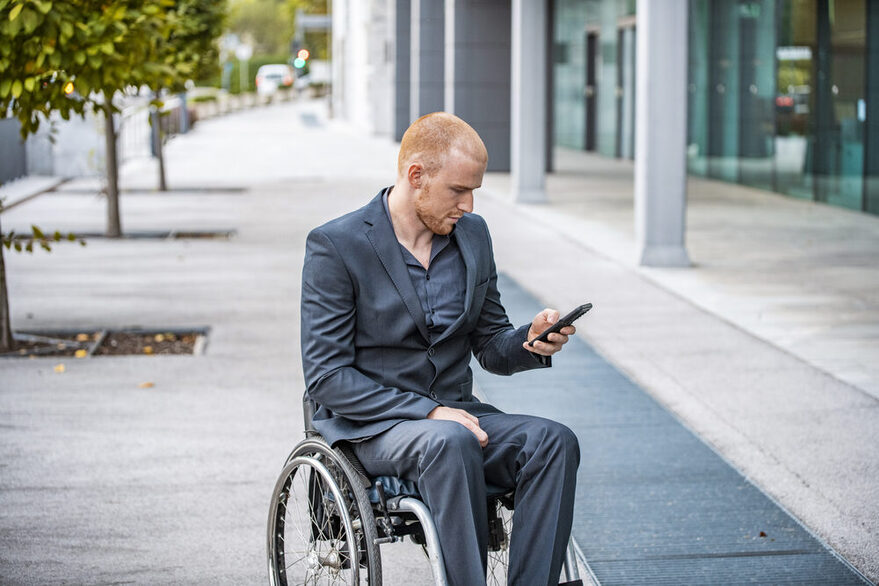 Businessman in Wheelchair Checking Smart Phone Outdoors
