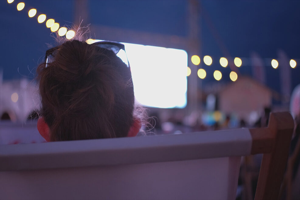 Eine Frau sitzt vor einer Kinoleinwand