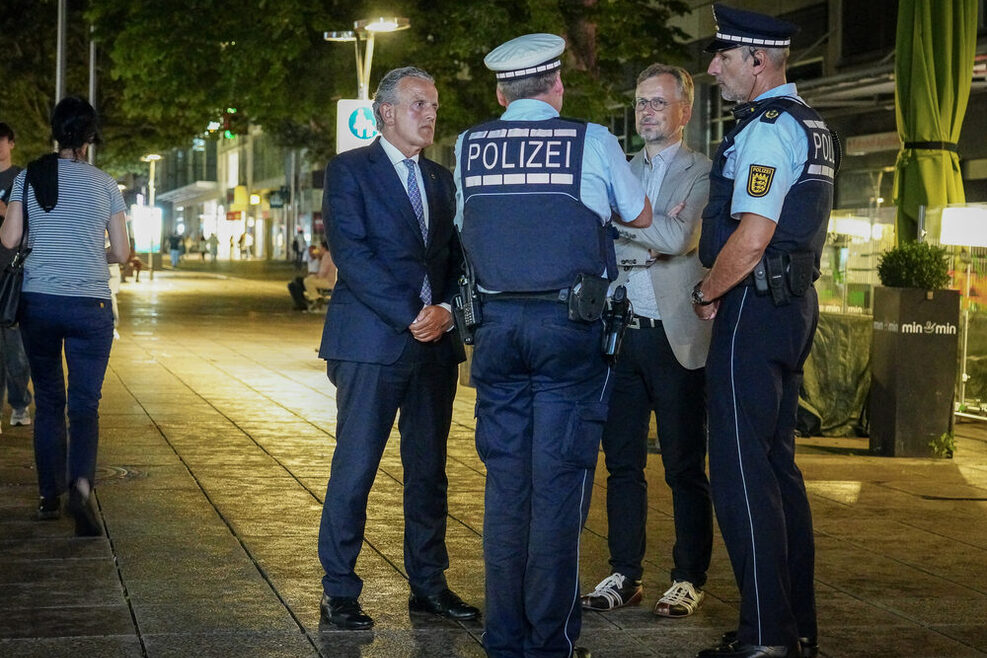 OB Nopper steht in der Nacht auf der Königstraße und unterhält sich mit Polizisten.