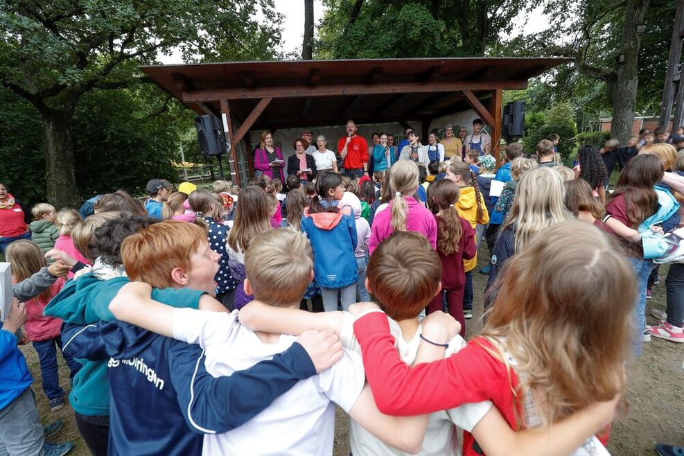 Die Kinder im Ferienwaldheim Möhringen beim gemeinsamen Singen. Auf der Bühne steht Isabel Fezer, Bürgermeisterin für Jugend und Bildung.