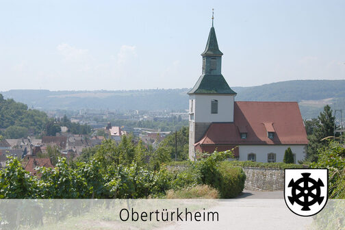 Blick auf die Petruskirche in Obertürkheim. Im Hintergrund sind Teile von Obertürkheim und Weinberge zu sehen.