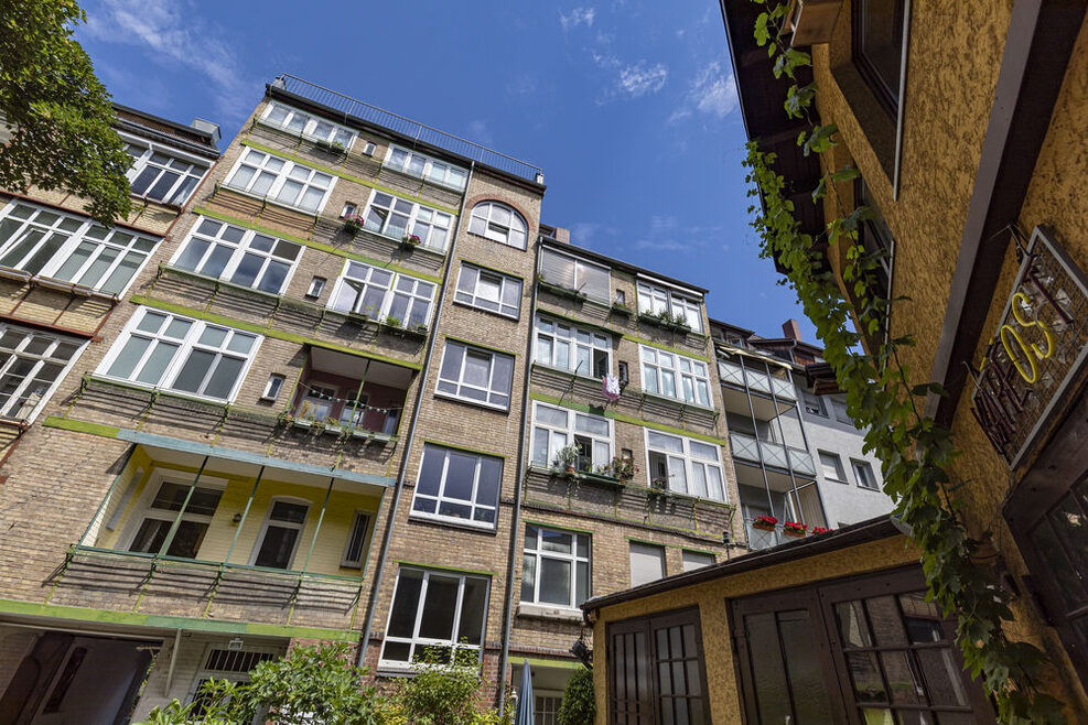 Blick aus einem Innenhof nach oben auf ein Wohnhaus.