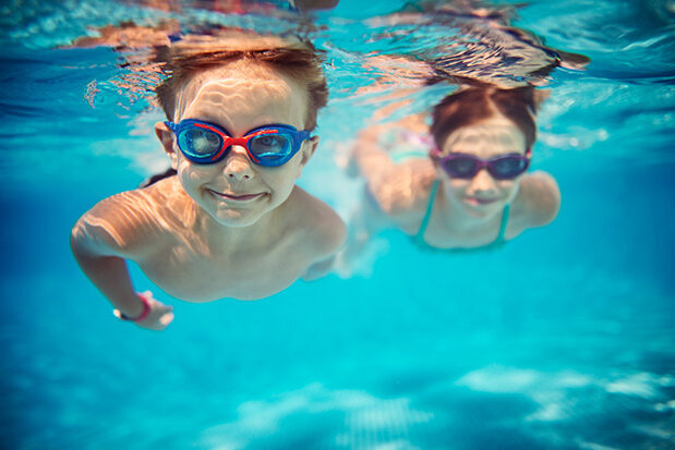 Fröhliche Kinder schwimmen unter Wasser