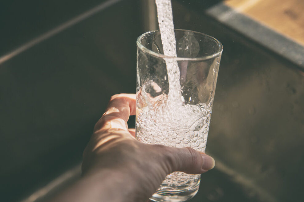 Wasser kommt aus dem Wasserhahn in ein Glas