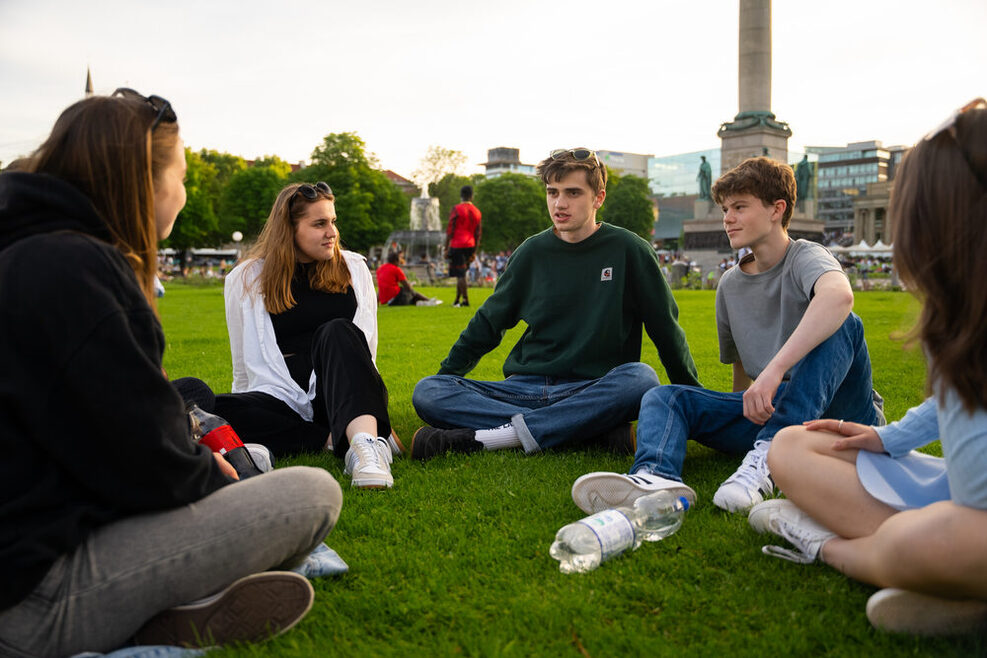 Stuttgarter Jugendräte sitzen auf der Wiese auf dem Schlossplatz