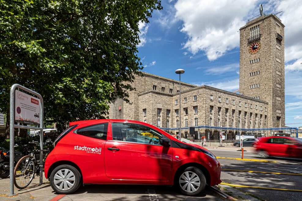 Ein rotes Auto steht vor einem historischen Gebäude mit einem Turm.