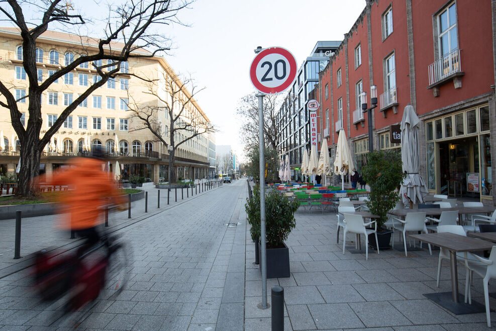 Blick in die Lautenschlagerstraße von der Bolzstraße her: Ein Radfahrer fährt die Straße entlang, rechts ist Außengastronomie zu sehen.