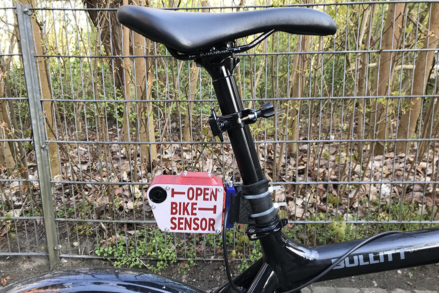Ein OpenBikeSensor ist an einem Fahrrad unterhalb des Sattels angebracht. Der Bildausschnitt zeigt den Sattel und den mit etwas Abstand darunter befestigten Sensor.