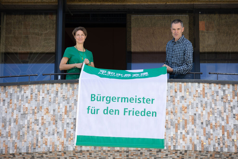 Bürgermeisterin Alexandra Sußmann entrollt die Flagge der Bürgermeister für den Frieden.