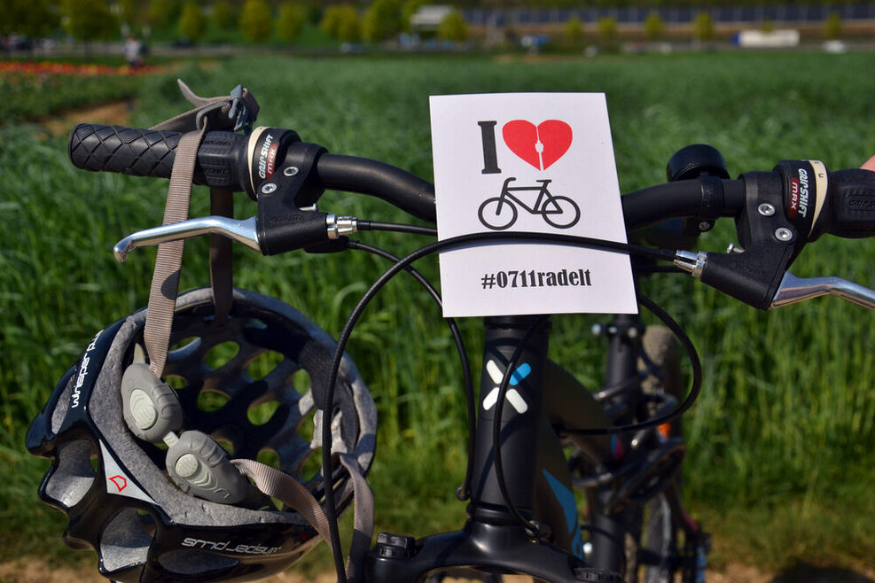 An einem Fahrradlenker hängt eine Postkarte mit dem Logo der Aktion Stadtradeln.