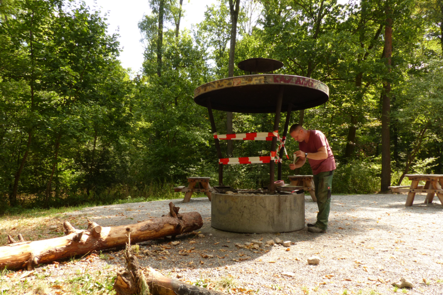 Ein Mitarbeiter des Forstamts sperrt eine Grillstelle mit Absperrband ab