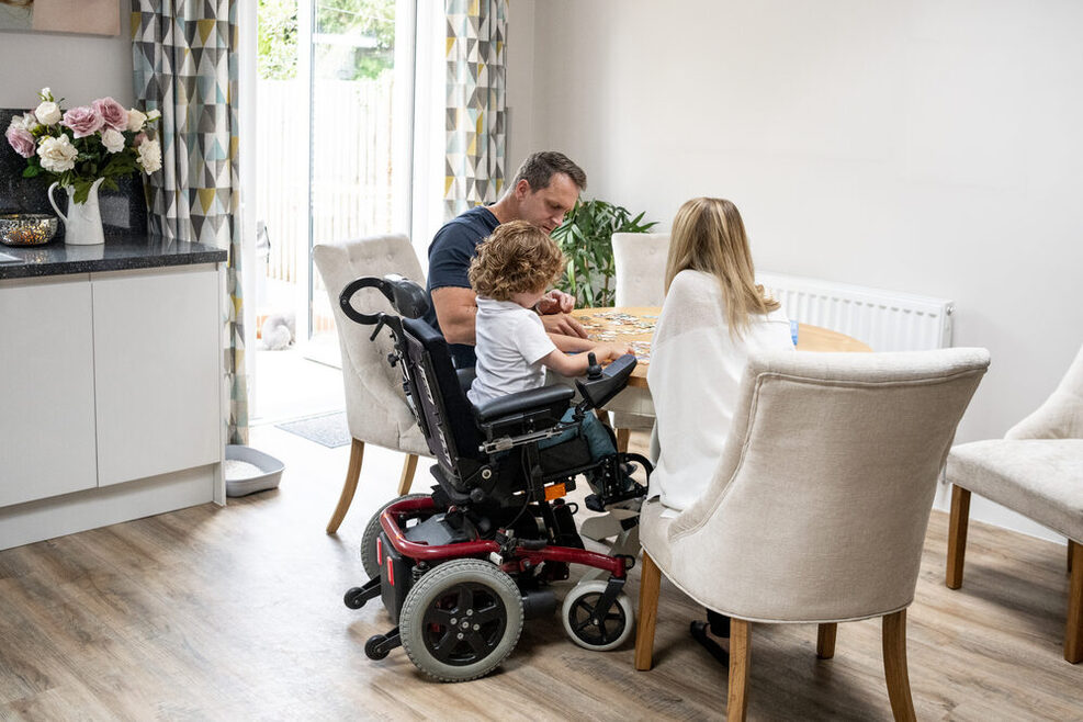 Boy in wheelchair doing jigsaw with parents