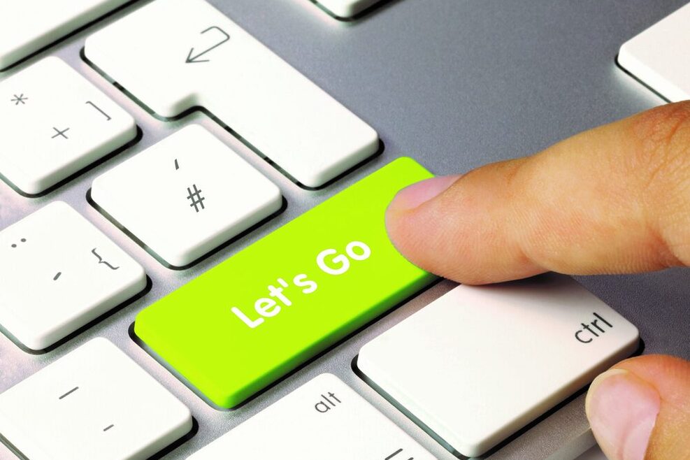 Ein Finger tippt auch eine Taste einer Tastatur. Auf der Taste steht geschrieben "Let's Go".