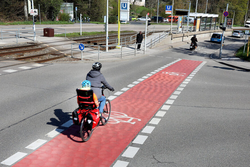 Markierung eines Radwegs auf der Kaltentaler Abfahrt. Eine Person mit Fahrrad fährt die Straße hinunter.