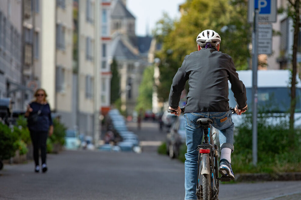 Ein Mann fährt auf dem Fahrrad durch die Stadt. Rückenansicht.
