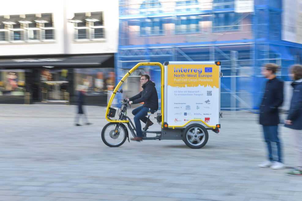 Ein mit Wasserstoff angetriebenes Lastenrad fährt über den Marktplatz in Stuttgart
