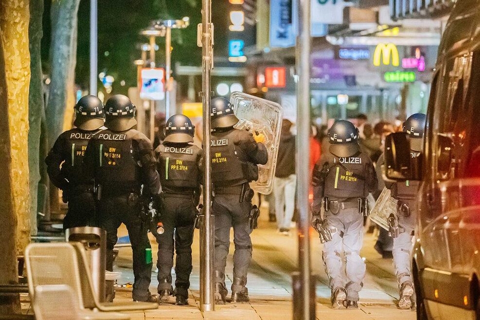 Polizisten in voller Montur nachts auf der Königstraße. Sie sind von hinten abgebildet.