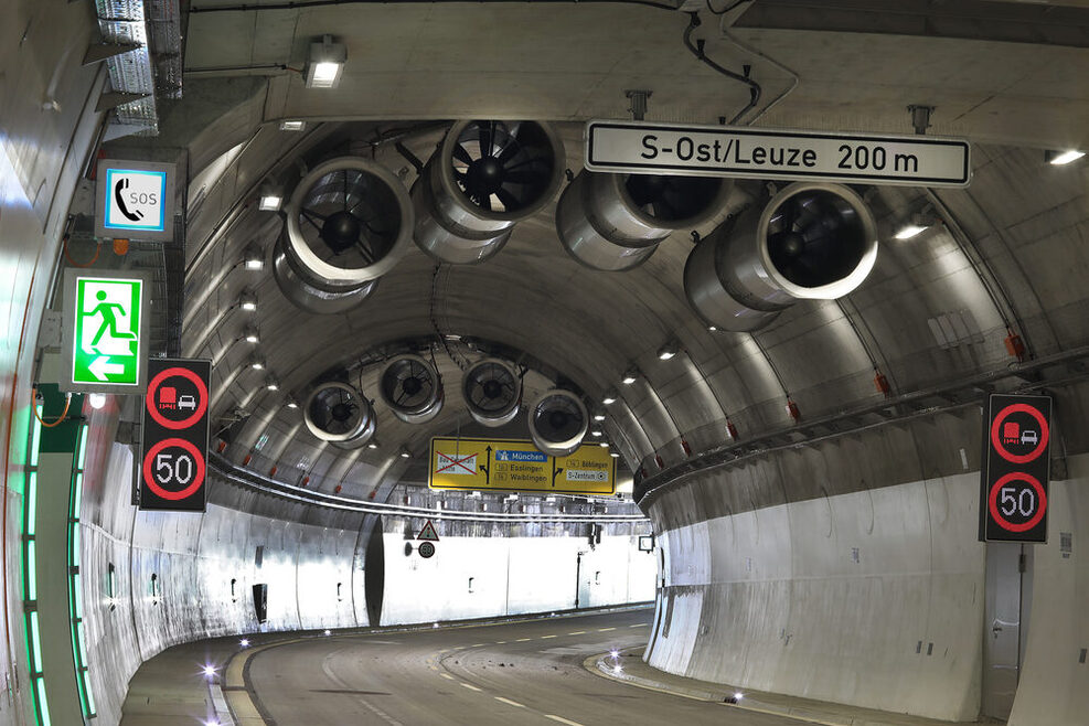 Blick aus dem Rosensteintunnel heraus. Es sind digitale Verkehrskennzeichen, große Ventilatoren und Straßenschilder zu sehen.
