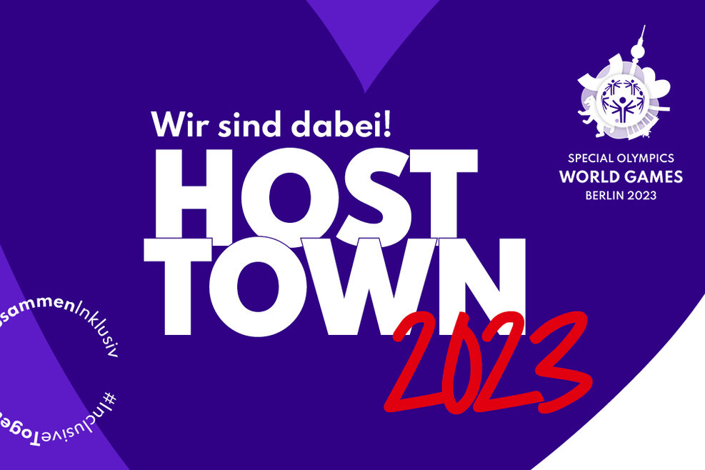 Das offizielle Logo des Host Town Programms der Special olympics World Games Berlin 2023. Zu sehen ist ein großes lilafarbenes Herz mit dem Schriftzug "Wir sind dabei! Host Town 2023"