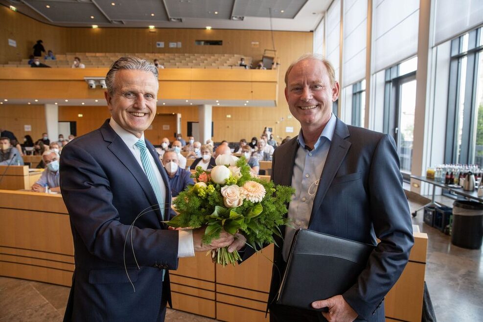 Oberbürgermeister Frank Nopper übergibt Jochen Jacker einen Blumenstrauß, beide lächeln in die Kamera