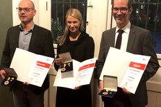 Daniel Benneweg, Annika Muras und Prof. Stefan Ehehalt halten die Ehrenmedaille und eine Urkunde in ihren Händen.