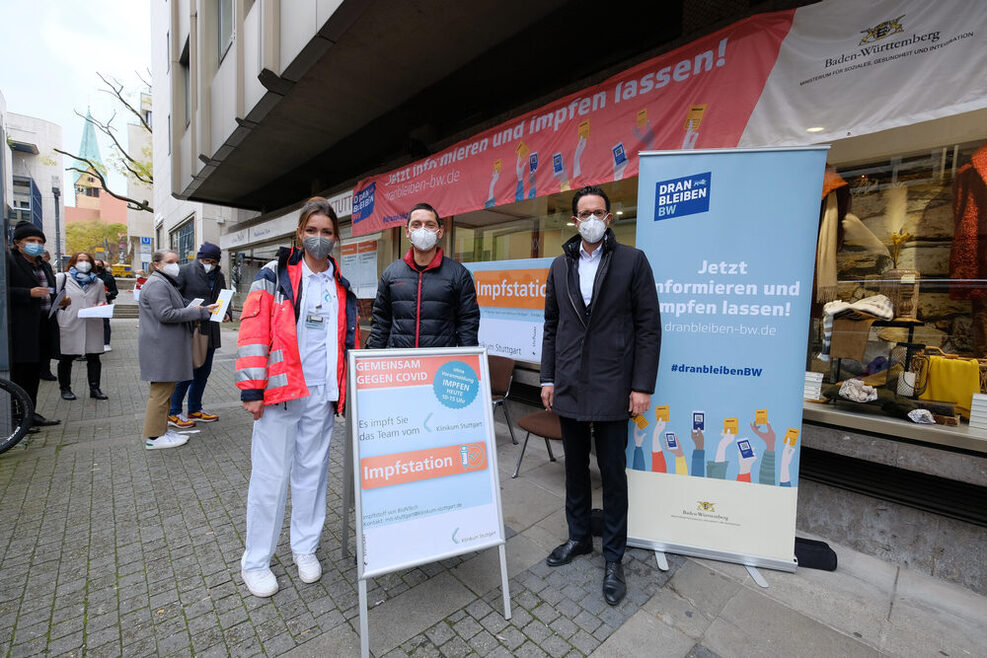 Carolin Wolfram und Dr. Christian Menzel vom Klinikum Stuttgart sowie der Erste Bürgermeister Dr. Fabian Mayer stehen vor der Impfstation.