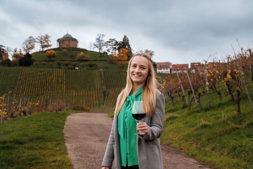 Weinprinzessin Birthe Meseke mit einem Glas Wein in den Stuttgarter Weinbergen und der Grabkapelle im Hintergrund