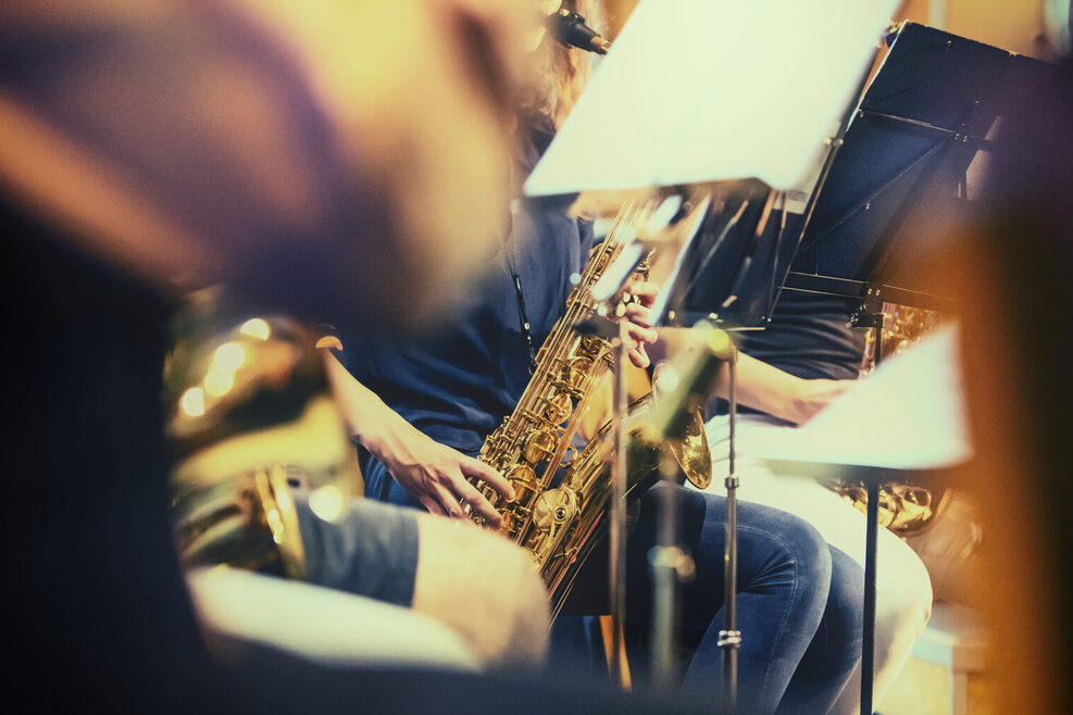 Saxophonspieler und andere Musiker spielen vor ihren Notenständern.