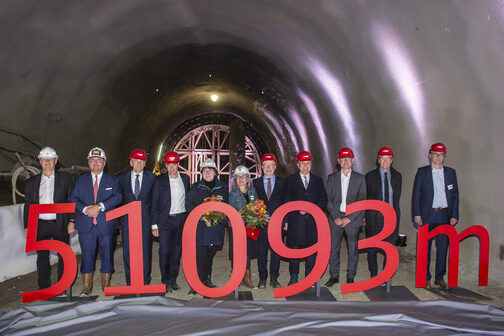 Eine Gruppe von Menschen steht in einer Tunnelröhre, vor ihnen große Zahlen und Buchstaben, die für 51093 Meter stehen..