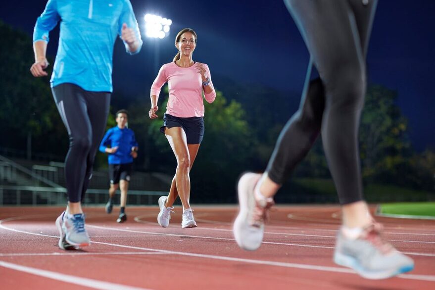 Läufer auf einer Sportanlage im Dunkeln unter Flutlicht