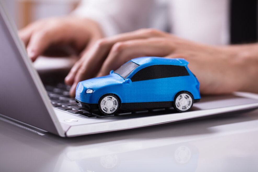 Ein kleines blaues Spielzeugauto steht auf der Tastatur eines Laptops