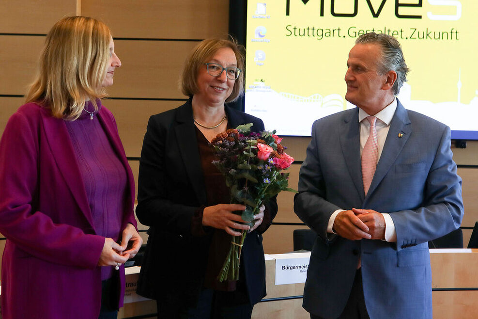 Links im Bild steht Bürgermeisterin Fezer, dann Abteilungsleiterin Straub in der Mitte mit einem Blumenstrauß und rechts Oberbürgermeister Dr. Nopper.