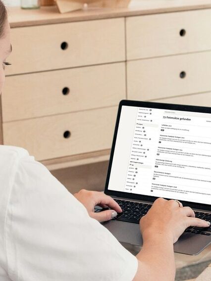 Frau sitzt vor einem Notebook und tippt etwas über die Tastatur ein