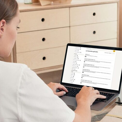 Frau sitzt vor einem Notebook und tippt etwas über die Tastatur ein