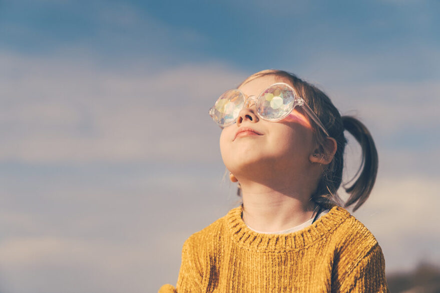 Mädchen schaut mit Brille in die Sonne