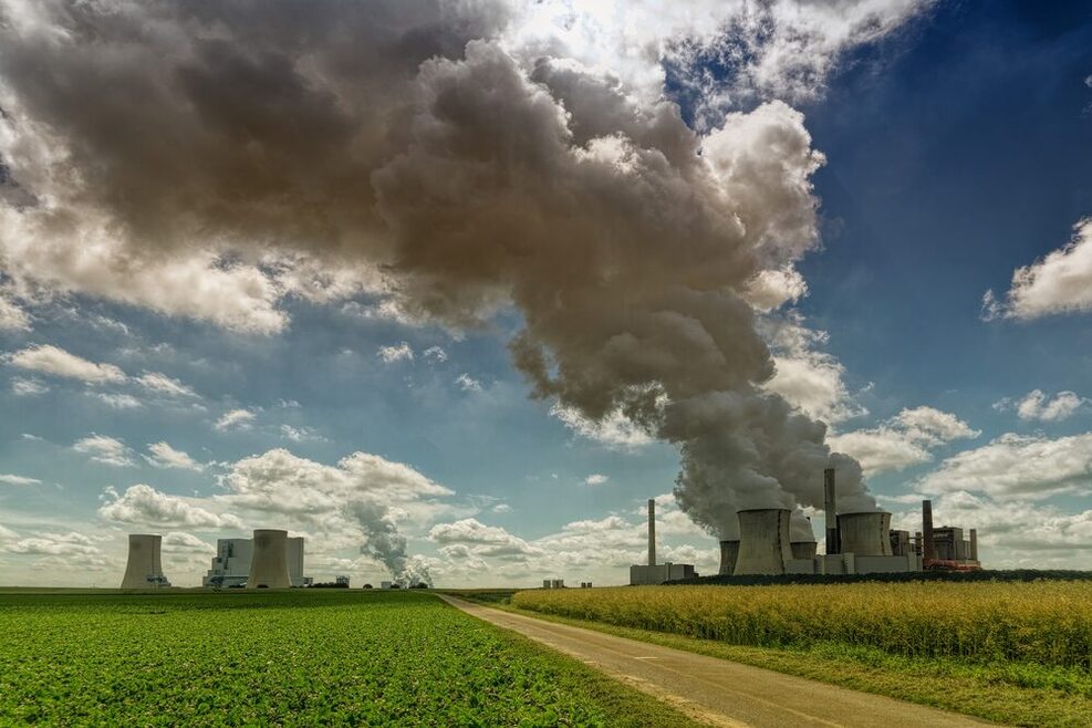 Braunkohle Kraftwerk mit starker Rauchentwicklung inmitten von grünen Feldern