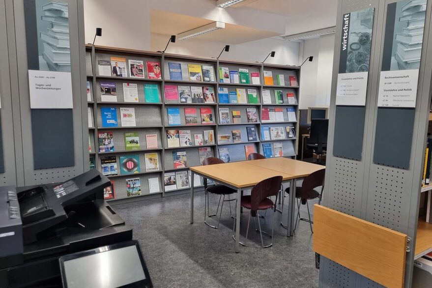 Leseraum der Rathausbibliothek mit Bücherregal, Tisch und Drucker.