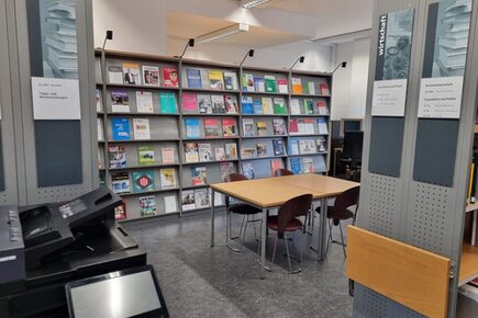 Leseraum der Rathausbibliothek mit Bücherregal, Tisch und Drucker.