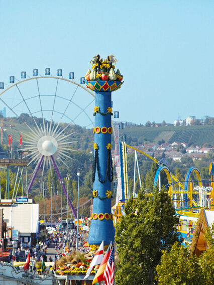 Luftaufnahme vom Cannstatter Volksfest: Zu sehen ist die Fruchtsäule, das Riesenrad und die Achterbahn.