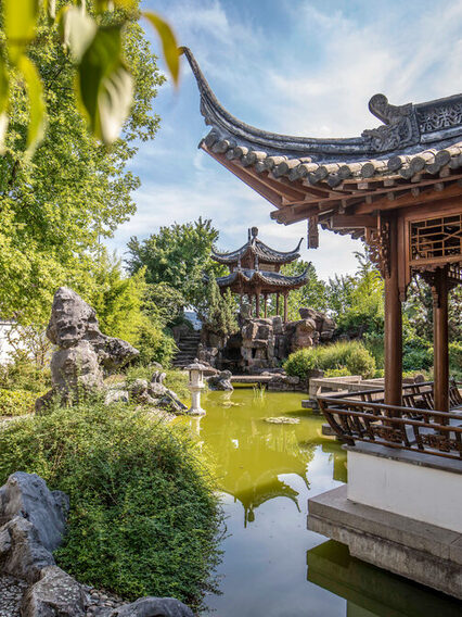 Chinesicher Garten mit kleinem Teich und Pavillons mit hochgezogenen Dachenden.