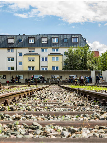 Gedenkfeier Gedenkstätte Nordbahnhof, Gleisverlauf im Hintergrund ist ein Haus