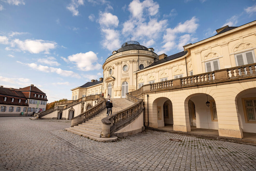 Außenansicht von Schloss Solitude: Zwei Menschen steigen die Freitreppen hinauf.