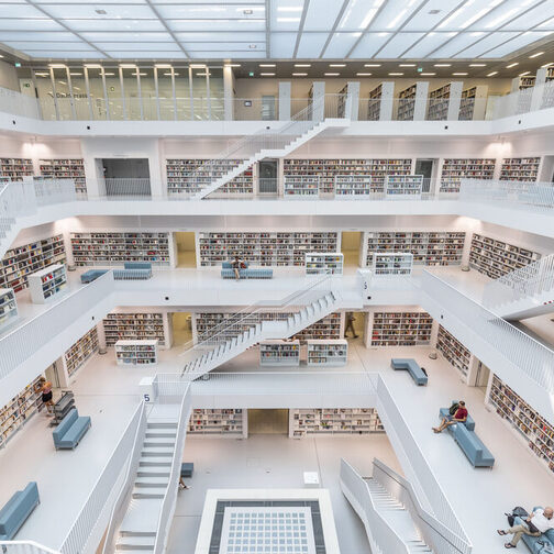 Der Innenraum der Stadtbibliothek hat eine Galerie über mehrere Ebenen mit Freitreppen. Alles ist in Weiß. Nur die Buchrücken setzen Farbakzente.