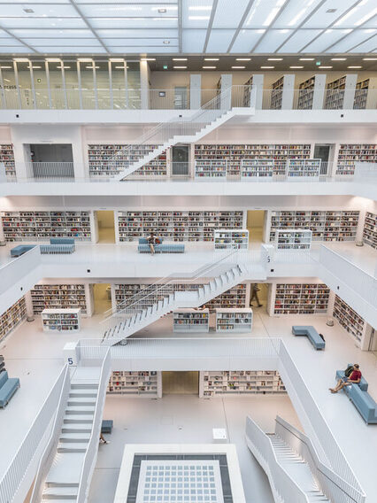 Der Innenraum der Stadtbibliothek hat eine Galerie über mehrere Ebenen mit Freitreppen. Alles ist in Weiß. Nur die Buchrücken setzen Farbakzente.