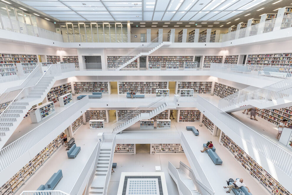 Der Innenraum der Stadtbibliothek hat eine Galerie über mehrere Ebenen mit Freitreppen. Alles ist in Weiß. Nur die Buchrücken setzen Farbakzente.