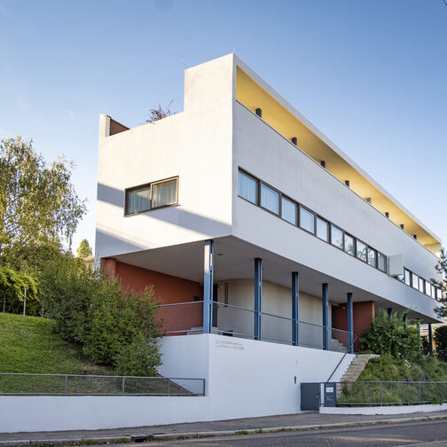 Außenansicht des Le Corbusier-Haus, mit weißer Fassade, langem Fensterband und klaren Linien.